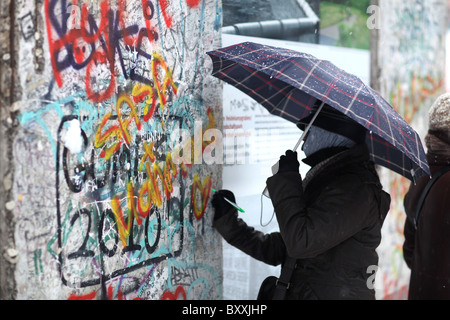 Ein Blick auf einige Touristen erhalten Teile der Berliner Mauer am Potsdamer Platz in Berlin, Deutschland. Stockfoto