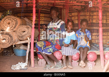 In der Fulani Dorf von Jolooga in nördlichen Burkina Faso sitzt eine Familie auf einem traditionellen Bett in einem Haus von handgewebten Teppichen aus. Stockfoto