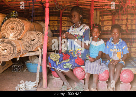 In der Fulani Dorf von Jolooga in nördlichen Burkina Faso sitzt eine Familie auf einem traditionellen Bett in einem Haus von handgewebten Teppichen aus. Stockfoto