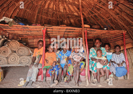 In der Fulani Dorf von Jolooga in nördlichen Burkina Faso sitzt eine Familie auf einem traditionellen Bett in einem Haus von handgewebten Teppichen aus. Stockfoto