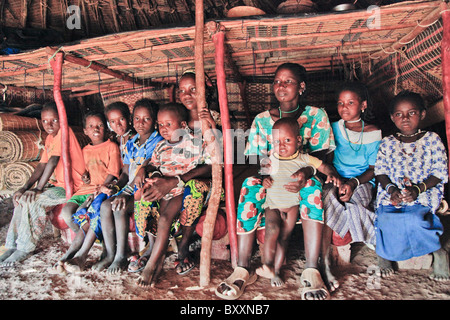 In der Fulani Dorf von Jolooga in nördlichen Burkina Faso sitzt eine Familie auf einem traditionellen Bett in einem Haus von handgewebten Teppichen aus. Stockfoto