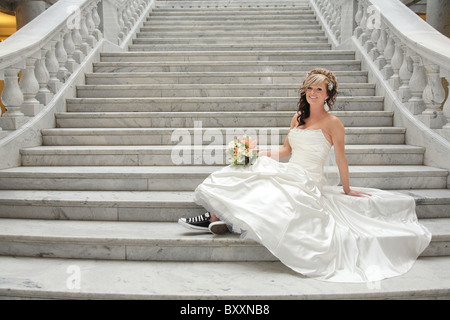 ziemlich zeitgenössische blonde Braut sitzt auf der Treppe Lächeln Stockfoto