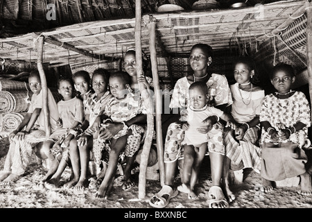 In der Fulani Dorf von Jolooga in nördlichen Burkina Faso sitzt eine Familie auf einem traditionellen Bett in einem Haus von handgewebten Teppichen aus. Stockfoto