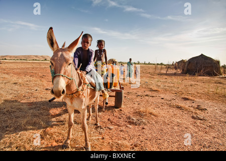 Zwei Fulani Kinder kehren in das Dorf Jolooga im Norden Burkina Faso nach Sammeln von Wasser aus einem nahe gelegenen Teich. T Stockfoto