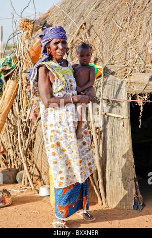 In Fulani-Dorf der Jolooga im nördlichen Burkina Faso stehen Dorfbewohner vor einem traditionellen Haus aus Stroh hergestellt. Stockfoto