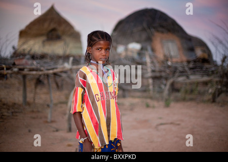 In den abgelegenen Fulani Dorf von Pete Goonga im nördlichen Burkina Faso, steht eine Fulani-Mädchen vor zwei Hirse-Graineries. Stockfoto