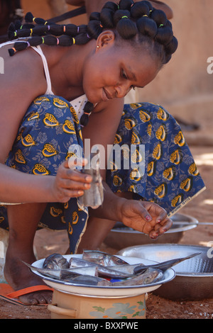 Eine Fulbe-Frau im nördlichen Burkina Faso inspiziert frischen Fisch, die sie braten und Hinzufügen einer Maniok-Couscous (Attieke). Stockfoto