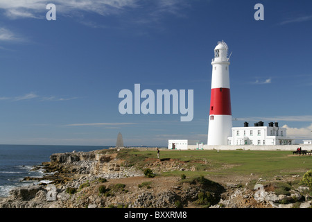 Portland Bill Leuchtturm in weiß und rot vor blauem Himmel, mit Meer und Felsen. Stockfoto