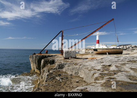 Portland Bill Leuchtturm über einen alten Kran auf den Felsen direkt am Meer, mit einem Ruderboot im Vordergrund angezeigt. Stockfoto