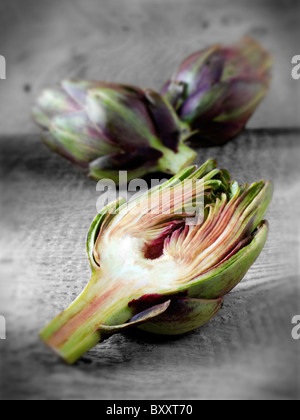 Die Side Shot frische Artischocken (Cynara Cardunculus) gegen einen Holz Hintergrund Stockfoto