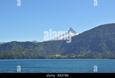 Blauer Himmel-Blick auf die Spitzen Volcan Puntiagudo, über einem gemäßigten Regenwaldes Hang, Todos Los Santos See, Chile Stockfoto