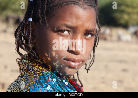In einem saisonalen Fulani-Dorf im nördlichen Burkina Faso tanzen Reflexionen von Pailletten von einer jungen Frau Schal im Gesicht. Stockfoto
