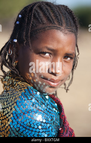 In einem saisonalen Fulani-Dorf im nördlichen Burkina Faso tanzen Reflexionen von Pailletten von einer jungen Frau Schal im Gesicht. Stockfoto