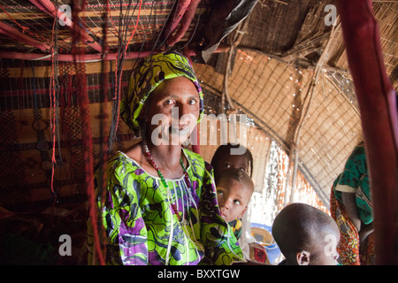 In der saisonalen Dorf Bantagiri im Norden Burkina Faso sitzt eine Fulbe-Frau mit ihren Kindern in ein Haus aus Stroh Mat. Stockfoto