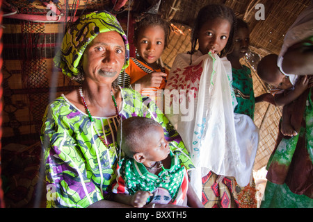 In der saisonalen Dorf Bantagiri im Norden Burkina Faso sitzt eine Fulbe-Frau mit ihren Kindern in ein Haus aus Stroh Mat. Stockfoto