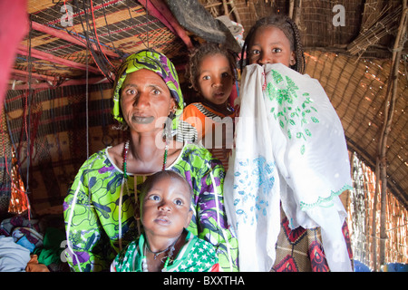 In der saisonalen Dorf Bantagiri im Norden Burkina Faso sitzt eine Fulbe-Frau mit ihren Kindern in ein Haus aus Stroh Mat. Stockfoto