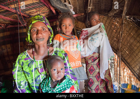 In der saisonalen Dorf Bantagiri im Norden Burkina Faso sitzt eine Fulbe-Frau mit ihren Kindern in ein Haus aus Stroh Mat. Stockfoto