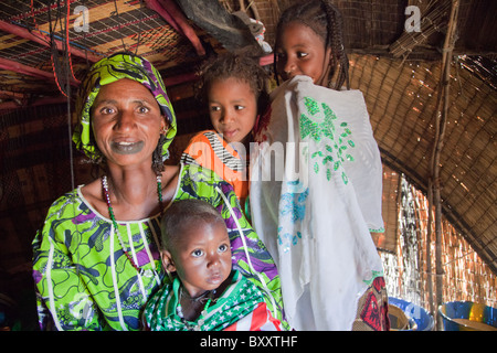 In der saisonalen Dorf Bantagiri im Norden Burkina Faso sitzt eine Fulbe-Frau mit ihren Kindern in ein Haus aus Stroh Mat. Stockfoto