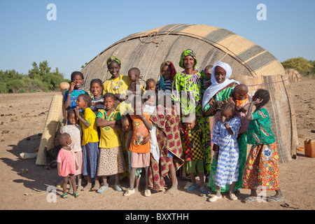 In der saisonalen Dorf Bantagiri im Norden Burkina Faso stehen Fulani Frauen und Kinder draußen ein Haus aus Stroh Mat. Stockfoto