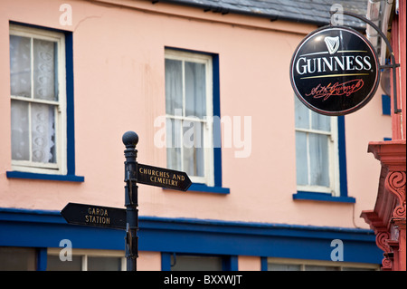 Wegweiser nach Garda, Kirchen und Friedhof neben Guinness Werbung am Bar in Timoleague, West Cork, Irland Stockfoto