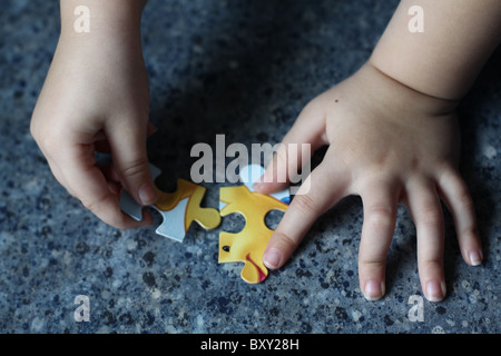 Eine Nahaufnahme von einem kleinen Kind Hände, Puzzleteile zusammenfügen. Stockfoto