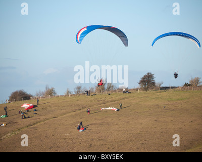 Piloten fliegen die Gleitschirme am Milk Hill nördlich von Alton Barnes, in der Nähe von Marlborough in Wiltshire, England. Stockfoto