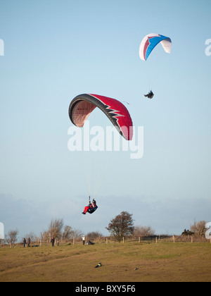 Piloten fliegen die Gleitschirme am Milk Hill nördlich von Alton Barnes, in der Nähe von Marlborough in Wiltshire England bei super Wetter. Stockfoto