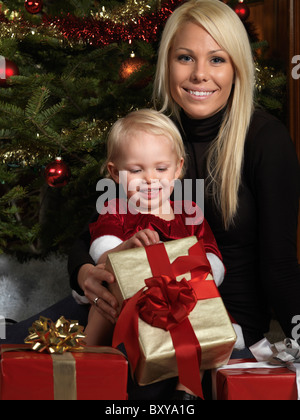 Porträt einer Mutter und ihrer Tochter Eröffnung präsentiert unter einem Weihnachtsbaum Stockfoto