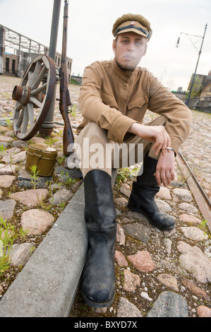 Soldat in Uniform des ersten Weltkrieges, hinsetzen, ruht auf dem Bürgersteig und Rauchen. Kostüm Accord Zeiten Weltkrieg I. Foto Stockfoto