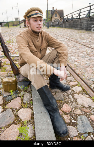 Soldat in Uniform des ersten Weltkrieges, hinsetzen, ruht auf dem Bürgersteig und Rauchen. Kostüm Accord Zeiten Weltkrieg I. Foto Stockfoto