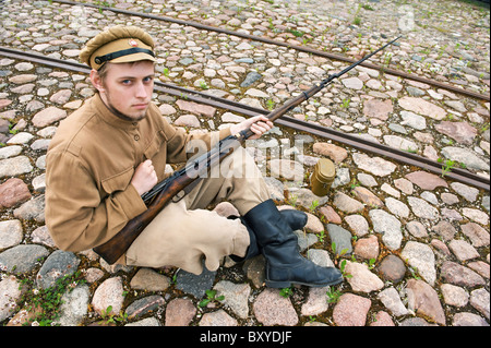 Soldat mit Gewehr und Kessel in Uniform des ersten Weltkrieges, Sit down und ruhen auf dem Bürgersteig. Kostüm Accord die Zeiten der Welt W Stockfoto