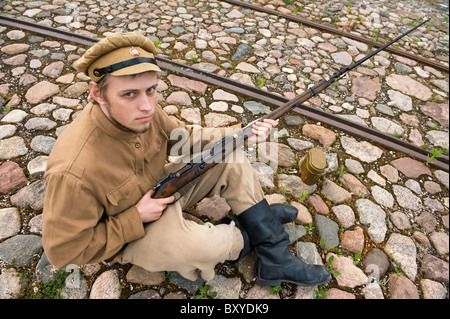 Soldat mit Gewehr und Kessel in Uniform des ersten Weltkrieges, Sit down und ruhen auf dem Bürgersteig. Kostüm Accord die Zeiten der Welt W Stockfoto