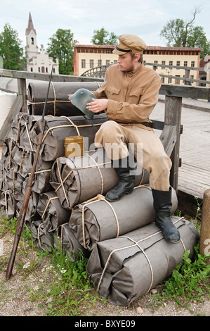 Soldat mit Helm und Gewehr auf die Bündel zu sitzen. Kostüm-Accord gemacht die Zeiten Weltkrieg I. Foto im Kino City Cinevilla Stockfoto