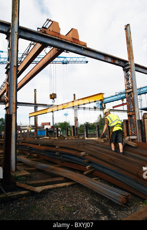 Konkrete Verstärkung: Arbeiter mit Stahl Rebar Stack im Fabrikhof Stockfoto