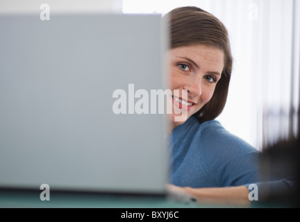 Frau im Büro von hinten Laptop spähen und lächelnd Stockfoto