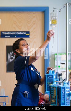 Eine Krankenschwester bereitet eine Kochsalzlösung Tropf auf einer Krankenstation UK Stockfoto