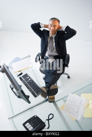 Geschäftsmann mit Füßen auf Schreibtisch Lächeln Stockfoto