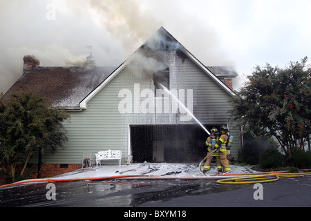 Feuerwehrleute arbeiten gemeinsam daran, ein Haus Feuer in Charlottesville, Virginia. Stockfoto