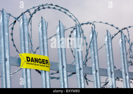 Warnschild Warnung vor Ziehharmonika-Rasiermesserdraht auf verzinktem Stahl montiert wies Zaun. Stockfoto