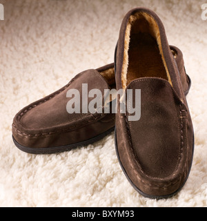 ein paar Herren braun Slipper Schuhe auf einem Schaffell Fleece-Hintergrund Stockfoto