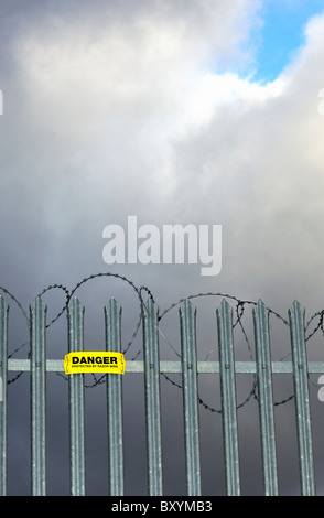 Warnschild Warnung vor Ziehharmonika-Rasiermesserdraht auf verzinktem Stahl montiert wies Zaun. Stockfoto