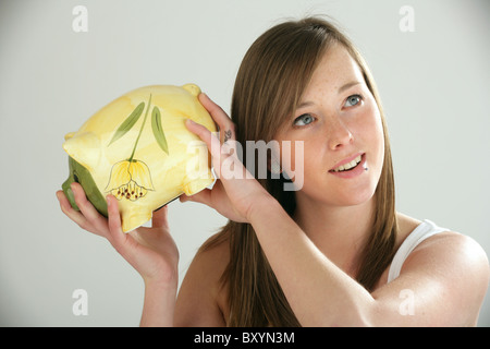 Hübsche Frau hält ein Sparschwein. Stockfoto