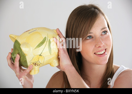 Hübsche Frau hält ein Sparschwein. Stockfoto