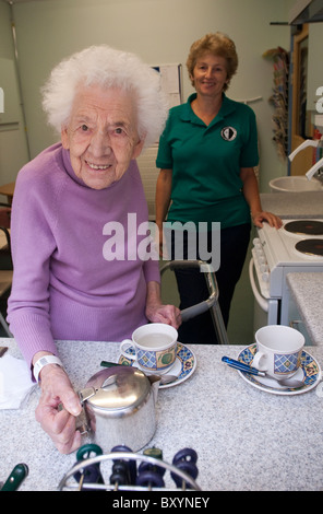 Eine ältere Frau macht es sich eine Tasse Tee unter dem wachsamen Auge von einem Schlaganfall Rehabilitation Krankenschwester UK Stockfoto