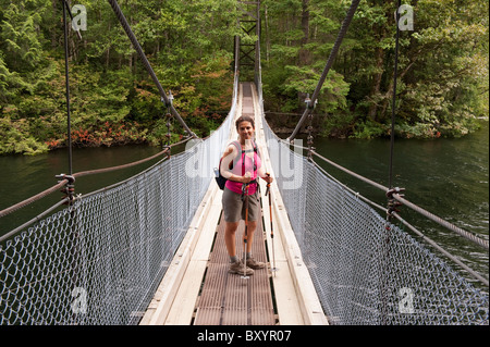 Hispanic Frau wandern über Brücke im Wald Stockfoto