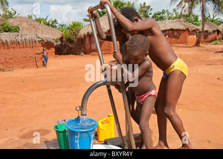 Kinder Pumpwasser aus einem Brunnen im ländlichen Afrika aus einem Brunnen von einer NGO als Bestandteil eines Trinkwasser-Projekts installiert. Stockfoto