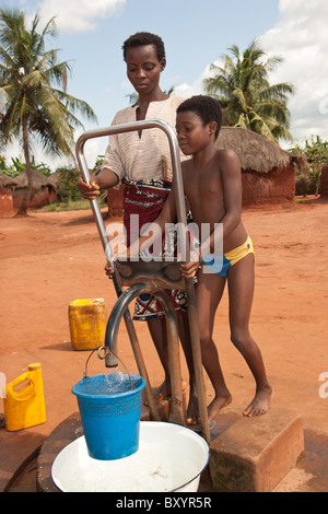 Ein Erwachsener und Kind Pumpe Wasser aus einem Brunnen im ländlichen Afrika aus einem Brunnen von einer NGO als Bestandteil eines Trinkwasser-Projekts installiert. Stockfoto