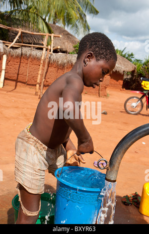 Durch die Dorfkinder in Westafrika ist sauberes gesundes Wasser aus einem Brunnen gepumpt. Die Pumpe wurde von einer NGO installiert. Stockfoto