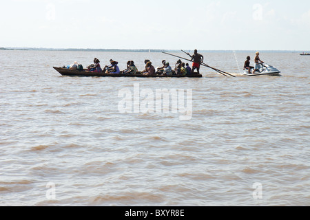 Traditionelle westafrikanisches Kanu transportiert Dorfbewohner von Togoville in Lac Togo, während moderne Jet-Ski durch Reißverschlüsse. Stockfoto