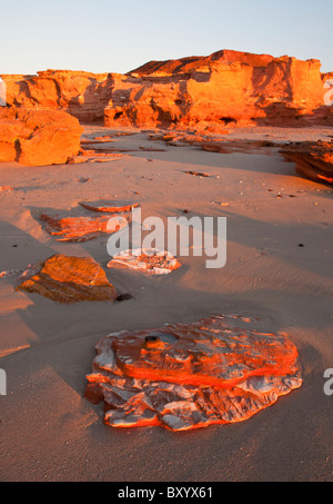 Goldener Sonnenuntergang am roten Pindan rockt in Barn Hill Station Strand, Broome, Kimberley, Western Australia Stockfoto